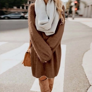 Close-up of a loose brown knit dress with a beige scarf and a brown leather clutch