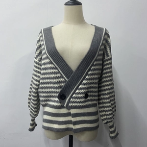 Détail d'un cardigan en tricot rayé gris et blanc avec col en V et gros boutons noirs