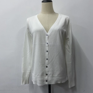 Detailed view of white V-neck knitted cardigan with dark buttons and ribbed cuffs