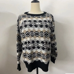 Vue détaillée des poignets côtelés et du motif géométrique argyle sur le pull en maille