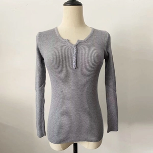 Detail of grey ribbed knit sweater featuring V-neckline with nine decorative buttons