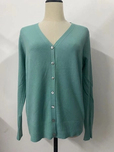 Detail of mint green V-neck cardigan with seven front buttons and ribbed knit cuffs