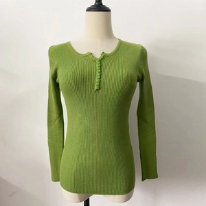 Detail of green ribbed knit sweater showing textured fabric and buttoned neckline