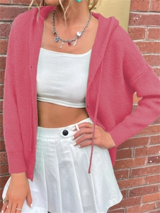 Detail of pink cable knit hooded cardigan texture and silver charm necklace on a model