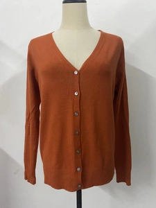 Detail of V-neck orange knit cardigan featuring six buttons and ribbed sleeve cuffs