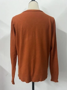 Detail view of the back of a burnt orange knit cardigan with ribbed hem and cuffs