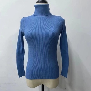 Detail of blue ribbed knit turtleneck sweater on beige mannequin with slim fit design