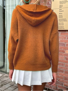 Macro detail of orange hooded knit cardigan with chunky ribbed texture and cozy loose fit