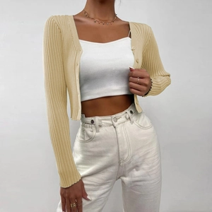 Detailed macro view of the ribbed knit fabric and button-down closure on the beige cardigan