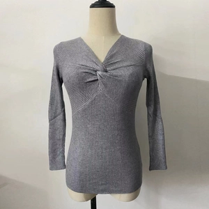 Detailed close-up of grey ribbed knit sweater featuring a twist front deep V-neckline