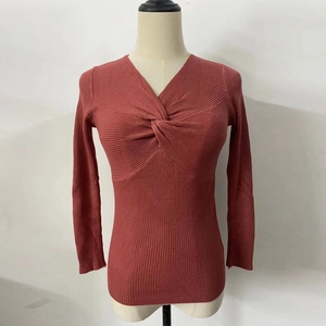 Close-up of ribbed knit texture with twisted knot detail and deep V-neckline in brick red