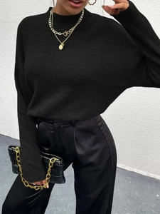 Detail eines schwarzen Rollkragenpullovers und einer Satinhose für den Business-Look