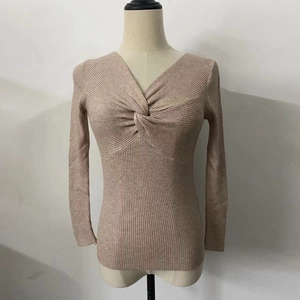 Close-up of beige knit top featuring a twist-knot V-neckline and ribbed texture