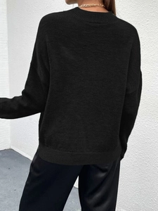 Detailansicht der Rückseite eines schwarzen Strickpullovers mit geripptem Saum und Bündchen