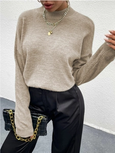 Detail eines hellkhakifarbenen Rollkragenpullovers mit Strickstruktur und eleganter Tasche