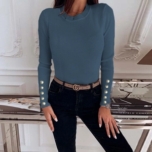 Close-up of ribbed knit texture on a long sleeve blue top with golden cuff button details