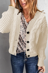 Detail of chunky cable knit cardigan in cream white with black buttons and relaxed fit