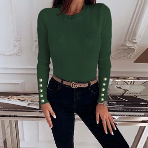 Detail of dark green ribbed knit sweater featuring elegant gold buttons on cuffs