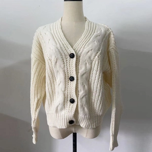 Detail of cream cable knit cardigan featuring contrast black buttons and textured ribbing