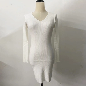 Dettaglio dell'abito in maglia bianca con scollo a V profondo e bordi a onde smerlate