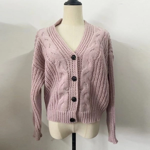 Detail of light pink cable knit cardigan featuring black buttons and ribbed cuffs