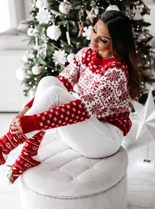 Détail du pull de Noël rouge en tricot avec des motifs festifs de flocons de neige blancs