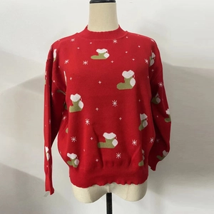 Détail du pull de Noël rouge avec motifs chaussettes vertes et flocons de neige blancs