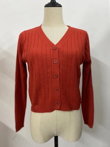 Gros plan d'un cardigan en maille rouge foncé avec texture côtelée et boutons assortis