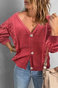 Detail of red knit cardigan featuring V-neckline and decorative silver diamond buttons