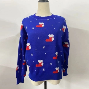 Détail d'un pull de Noël bleu en tricot avec des chaussettes rouges et flocons blancs