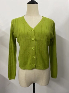 Détail d'un gilet en maille verte avec col en V, texture côtelée et boutonnage