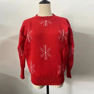 Detail of red Christmas sweater featuring white snowflake patterns and ribbed knit texture
