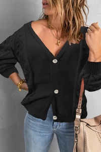 Detail of black knit cardigan featuring sparkling rhinestone buttons and hollow-out patterns
