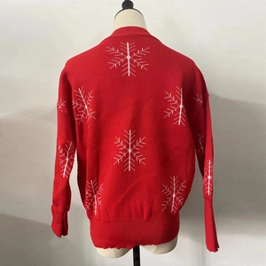 Detail of red Christmas knit sweater with white snowflake patterns and ribbed cuffs