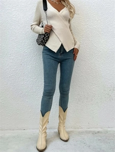 Gros plan sur un pull en maille côtelée beige avec col en V croisé et texture douce