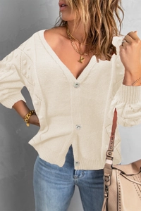 Detail of beige V-neck knit cardigan with textured dot patterns and rhinestone buttons