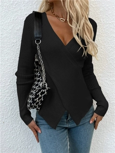 Détail du pull en maille côtelée noire avec ourlet asymétrique et design cache-cœur en V
