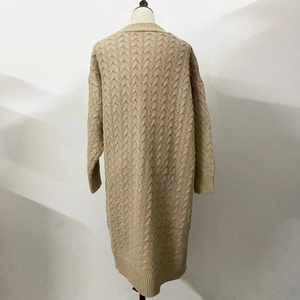 Close-up of cable knit patterns on long beige cardigan sweater with ribbed cuff details