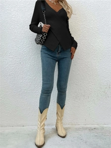 Détail du haut en maille croisée noire avec jean slim et bottes beiges élégantes