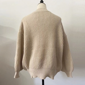 Macro detail of beige ribbed knit texture and loose batwing sleeve design on a sweater