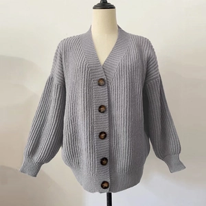 Detail of light purple chunky knit cardigan showing V-neck and tortoiseshell buttons