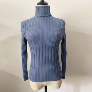 Detail showing the vertical ribbed knit texture and slim fit high neck grey-blue sweater