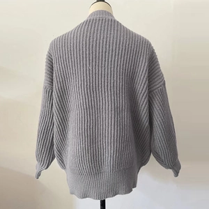 Macro view of gray chunky knit cardigan featuring drop shoulder and ribbed cuffs