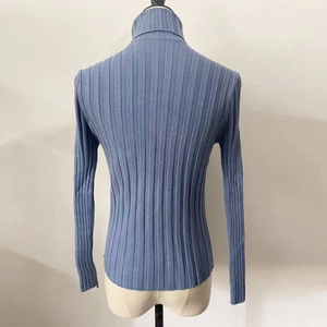 Detail view of the ribbed knit texture and high turtleneck design on blue sweater