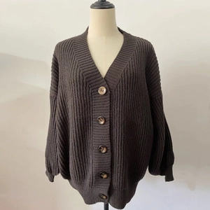 Close-up of rib-knit texture and wooden buttons on a dark brown loose V-neck cardigan