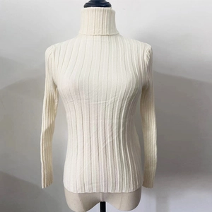 Detailed close-up of the off-white vertical ribbed texture on a turtleneck sweater