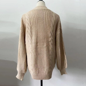 Detailed back view of a beige cable knit sweater featuring thick textured woven patterns