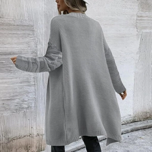 Detail of light gray chunky knit cardigan showing vertical texture and ribbed cuffs