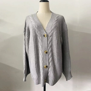 Detailed view of cable knit texture and large buttons on light grey cardigan sweater