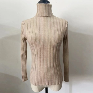 Close-up of oatmeal ribbed knit texture on slim fit high neck long sleeve sweater